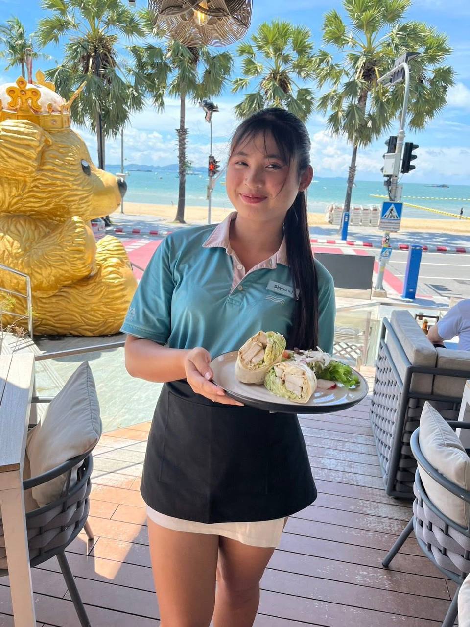 Server presenting fresh wraps with beachfront view